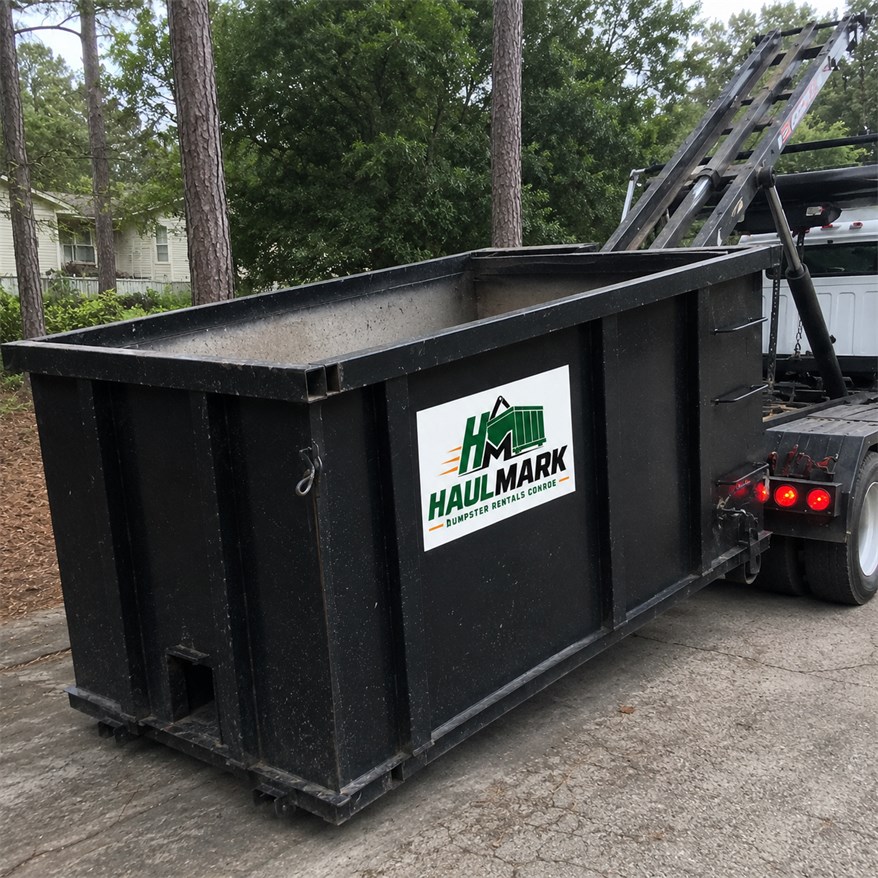 Haulmark dumpster positioned near a service truck for local delivery